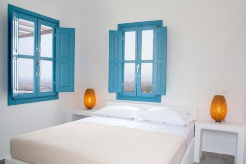een witte slaapkamer met blauwe ramen en een bed bij Oenotheras II by Thireon in Thólos