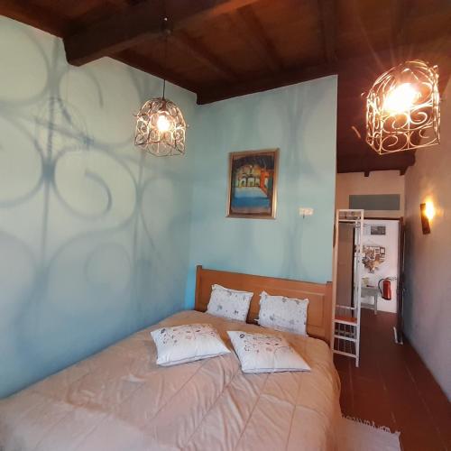 a bedroom with a bed with two pillows and two lights at Casa das Amoras in Santo António das Areias