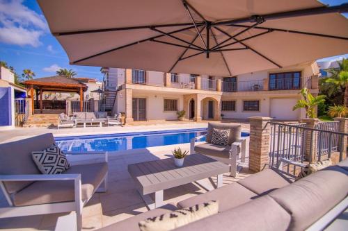 a patio with an umbrella and a swimming pool at Luxury Villa Christine sea view in El Campello