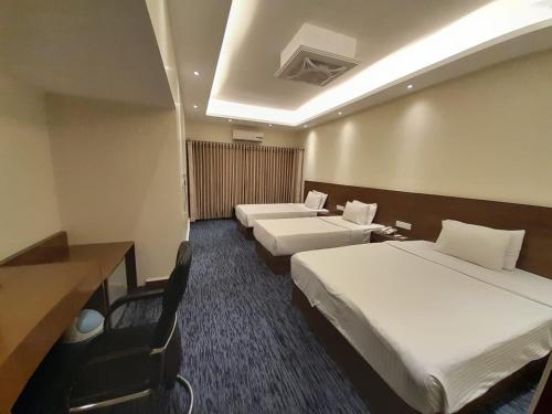 a hotel room with two beds and a desk at Richmond Hotel & Suites in Dhaka