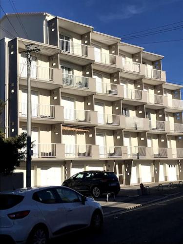 une voiture blanche garée devant un grand bâtiment dans l'établissement Appartement au Grau D'Agde, au Grau-dʼAgde