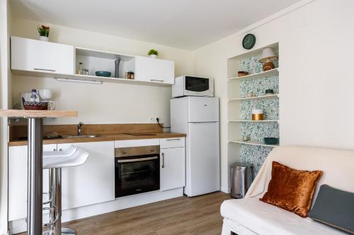 une cuisine avec des armoires blanches et un réfrigérateur blanc dans l'établissement LA TERRASSE - FIBRE - PARKING GRATUIT - Proche écoles et entreprises, à Orsay