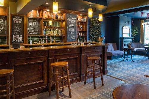 a bar in a pub with stools at The Lettered Board Apartments in Pickering