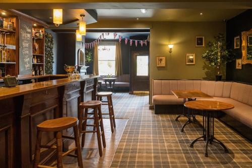 a bar in a pub with a couch and stools at The Lettered Board Apartments in Pickering