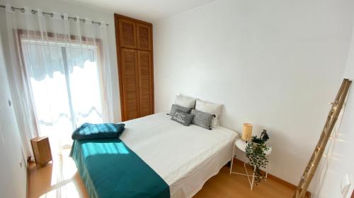 een slaapkamer met een wit bed met blauwe kussens bij Pleno Beach-side apartment Furadouro in Furadouro