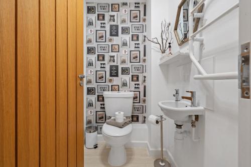 a bathroom with a toilet and a wall of pictures at Tincroft Cottage - high end, luxury living near the beach in Truro