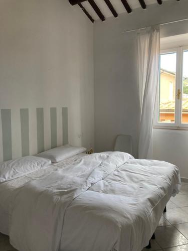 Cama blanca en habitación blanca con ventana en La casina, en Marciana Marina