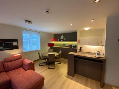 uma sala de estar com um sofá, uma mesa e uma cozinha em Edward Hopper Suite, Duinhof 3-9-7, spacious apartment near the beach with sunny balcony em Cadzand