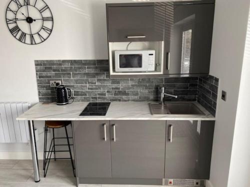 a kitchen with a sink and a microwave at Luxury Mumbles View Studio Apartment in Swansea