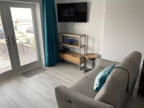 a living room with a couch and a television at Luxury Mumbles View Studio Apartment in Swansea