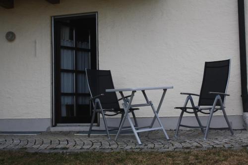 two chairs and a table in front of a building at Almberghütte in Philippsreut
