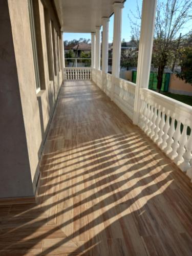a porch of a house with shadows on the ground at Tskaltubo Apartment Mirian Mepe in Tskaltubo