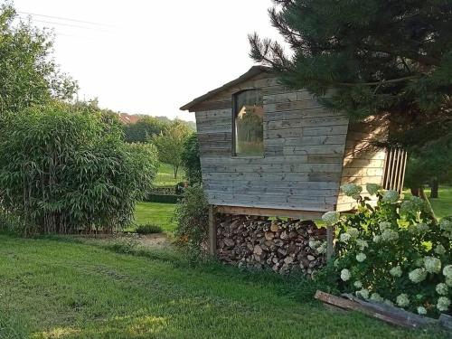 a small house with a stone wall in a yard at Le Clos des Marronniers in Ecques