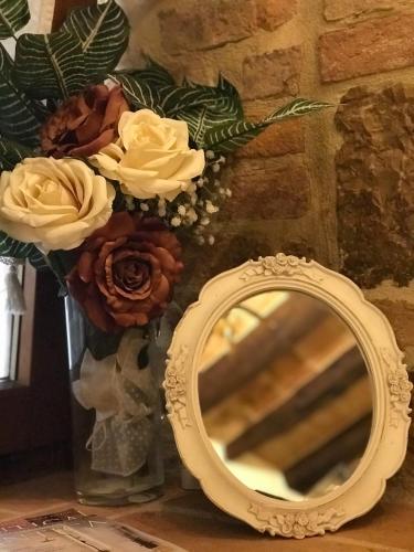 a vase with flowers and a mirror on a table at Residenza Teatro Antico in Todi