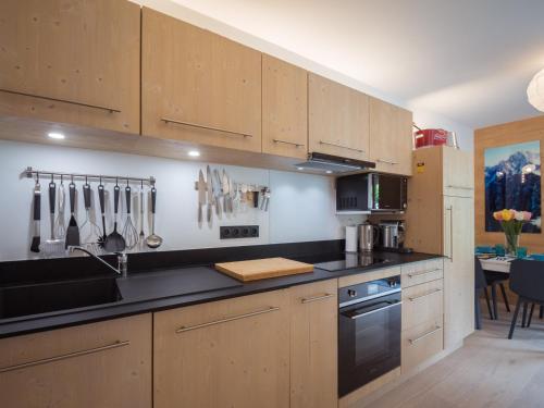 une cuisine avec des armoires en bois et un comptoir noir dans l'établissement Bel appart 4* avec jardin privé, à 350m de la Flégère, WIFI, PARKING - FR-1-343-213, à Chamonix-Mont-Blanc