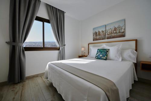 a bedroom with a large white bed and a window at ABLANCAS - La Restinga in La Restinga