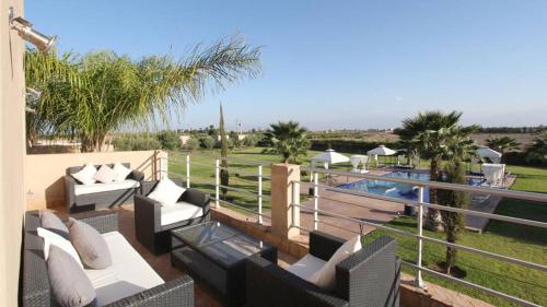 un patio con divani, piscina e palme di Luxury Villa near Marrakech a Zaouia El Hedil Mamra