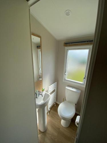 a bathroom with a toilet and a sink and a window at 3 Bed Static Caravan in Morecambe in Morecambe