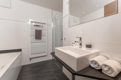 a white bathroom with a sink and a bath tub at Aparthotel Ambiente in Umhausen
