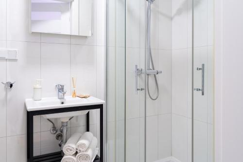 een witte badkamer met een douche en een wastafel bij Happy House Apartamenty in Krakau