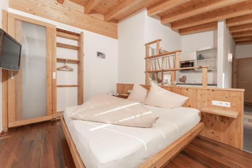 1 dormitorio con 1 cama blanca grande y TV en Aparthotel Ambiente en Umhausen