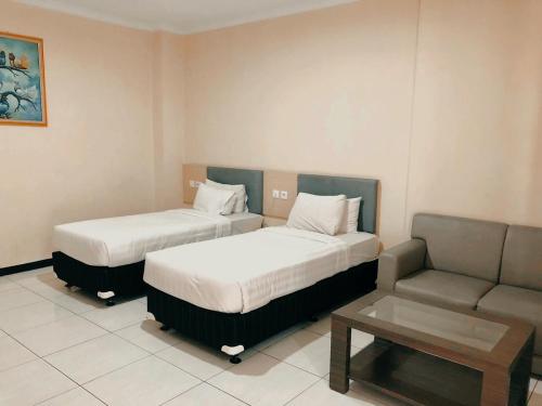 Habitación de hotel con 2 camas y sofá en Permata Inn Slawi, en Procot