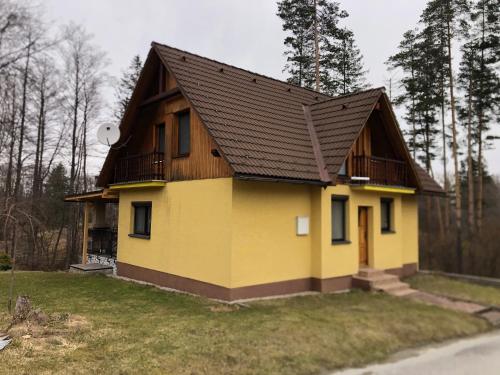 a yellow house with a brown roof at Chata Oravská Priehrada in Námestovo