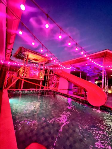 a pool with a water slide and purple lights at Slumber Party Krabi in Ao Nang Beach