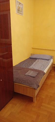 a small bed in a room with a yellow wall at Warszawska 