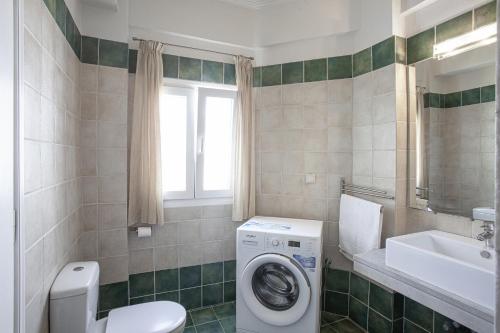 Kassiopi Seafront Elegant Apartments في كاسيوبي: حمام مع غسالة ومغسلة