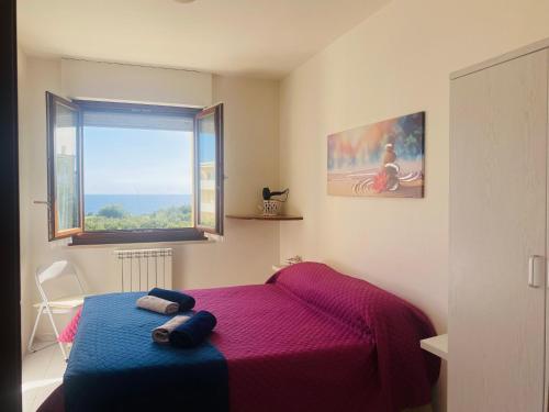 una camera con letto viola e finestra di Voce Del Mare - sea view- Alghero Airport ad Alghero