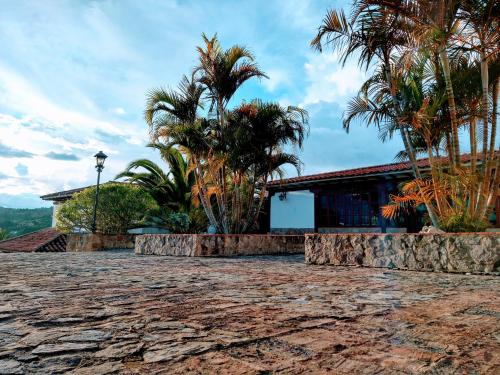 a house with palm trees and a stone driveway at Hotel Bosque de la Villa in Villa de Leyva