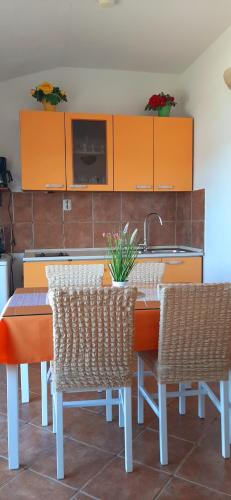 a kitchen with orange cabinets and a table and chairs at Apartment Pečarević - a holiday with a stunning view in Vis