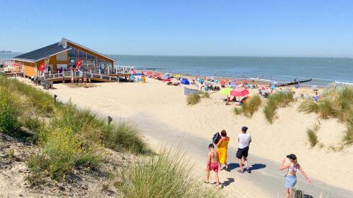 a group of people walking on a beach at Caramia, Duinhof, Romantic apartment by the sea in Cadzand-Bad