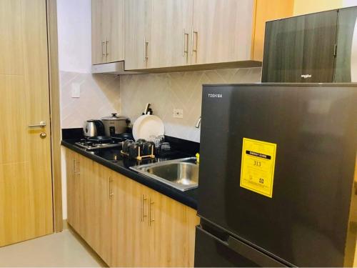 a kitchen with a black refrigerator and a sink at Resort Style Condo Walkable to Mall of Asia in Manila