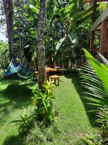 a garden with chairs and a hammock in the grass at Estudio Lirios seu cantinho ecológico na natureza in Marau
