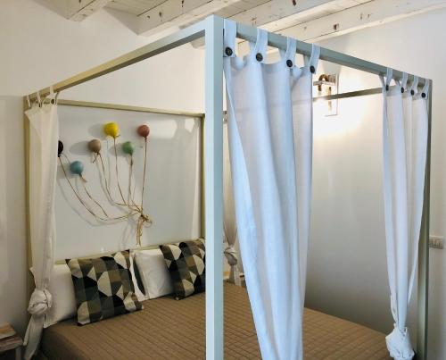 Atipico B&B في باري: سرير مظلة مع ستائر بيضاء في غرفة النوم