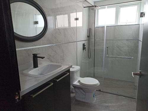 y baño con lavabo, aseo y espejo. en Lujoso Apartamento Frente al Estadio Bellavista en Ambato