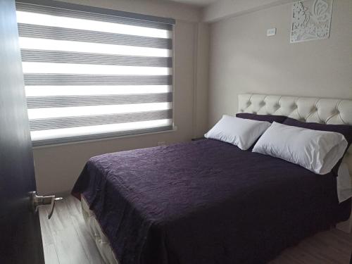 1 dormitorio con 1 cama grande y ventana en Lujoso Apartamento Frente al Estadio Bellavista, en Ambato