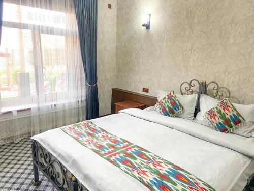 a bedroom with a bed with white sheets and a window at Evergreen Guesthouse in Margilan
