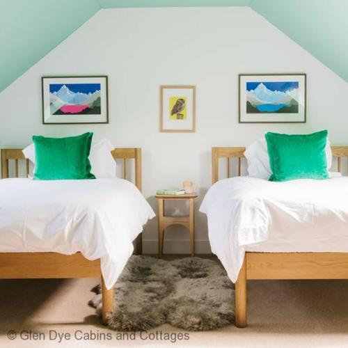a bedroom with two beds with green pillows at Number 2 Steading Cottage in Banchory