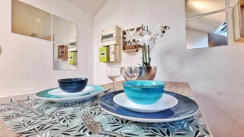 une table avec deux bols bleus et des verres dessus dans l'établissement Studio ONE - Musée Auto - Wifi - RBNB, à Mulhouse