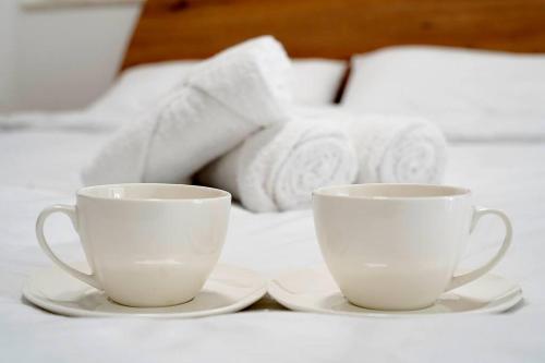 two white cups and saucers on a bed at Luxurious Apartment Next to the Sea in Il-Gżira