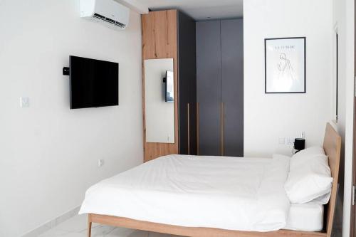 a bedroom with a white bed and a tv at Luxurious Apartment Next to the Sea in Il-Gżira
