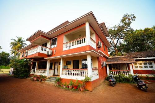 an orange house with a motorcycle parked in front of it at NomadGao Vila Nova - Comfort, Great Views, Fast WiFi & Interesting People in Anjuna