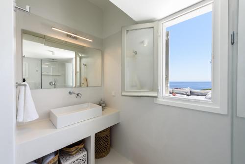a white bathroom with a sink and a window at VILLA NOSTOS ANTIPAROS in Antiparos