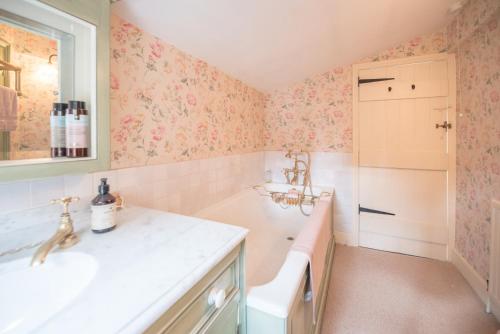 a bathroom with pink floral wallpaper and a sink at The Way Southwold in Southwold