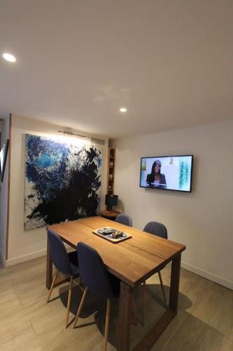 une table à manger avec des chaises et une télévision murale dans l'établissement Jolie appartement avec véranda proche de la place des lices, à Saint-Tropez