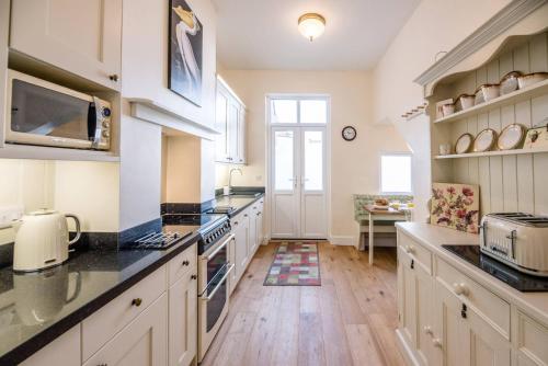 a kitchen with white cabinets and a counter top at No 12, Southwold in Southwold