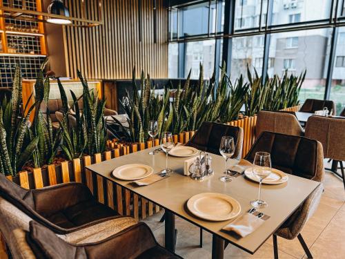 a table and chairs in a restaurant with plants at Favor Sport Hotel in Kyiv